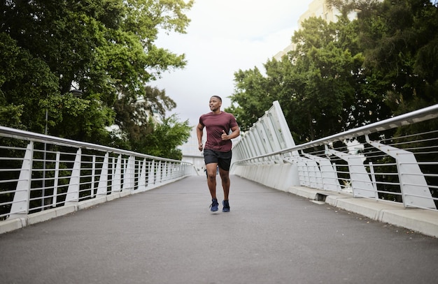 Running bridge e allenamento di atleta uomo di colore per la maratona, benessere e sport Allenamento cardio corridore veloce e allenamento fitness di un uomo che fa esercizio di salute su una strada urbana al mattino
