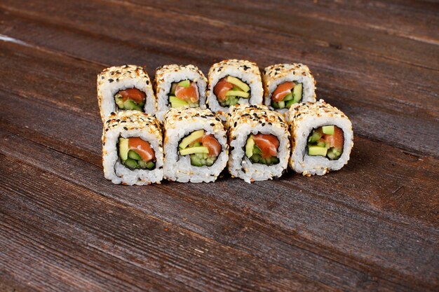 Ruoli di sushi fresco su un piatto di legno con le mani dello chef sullo sfondo