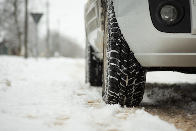 Ruota anteriore dell'auto su strada coperta di neve Guida invernale peculiarità stagionali del veicolo di guida