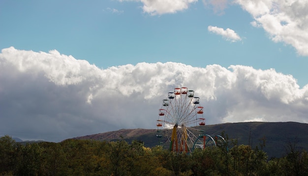 Ruota panoramica multicolore in montagna sullo sfondo del cielo e delle nuvole