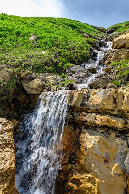 Ruscello di montagna con una cascata tra le montagne alpine bellissimo paesaggio con montagne verdi