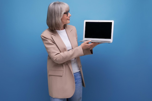 S donna in giacca che mostra il mockup dello schermo del laptop su sfondo luminoso con spazio per la copia