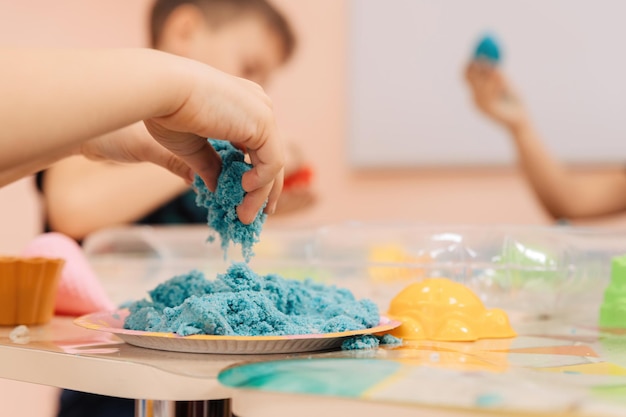 Sabbia cinetica. le mani dei bambini giocano con la sabbia polimerica multicolore.