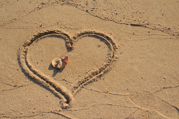 Sabbia della spiaggia attinta forma del cuore