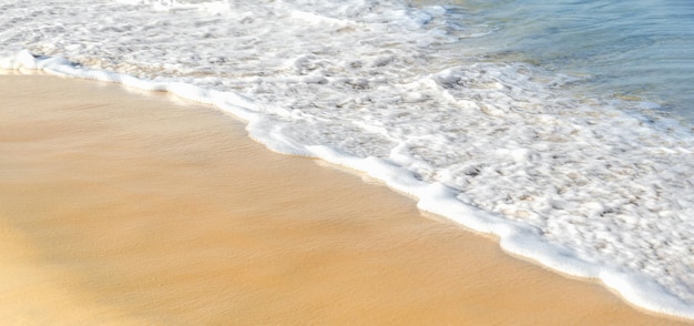 Sabbia dorata della schiuma bianca dell'onda blu del mare del fondo di vacanze estive di concetto di viaggio della costa di mare