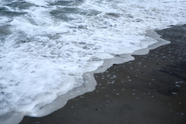 Sabbia sulla spiaggia con un'onda del mare