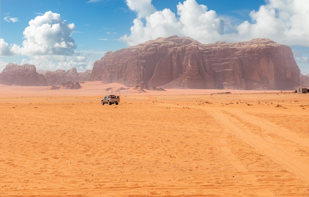 Sabbie arancioni e scogliere del deserto di Wadi Rum con auto turistica sullo sfondo Giordania