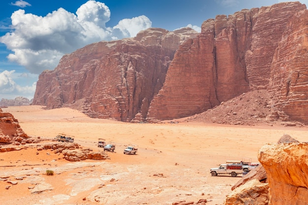 Sabbie e rocce arancioni del deserto di Wadi Rum con auto beduine in primo piano Giordania