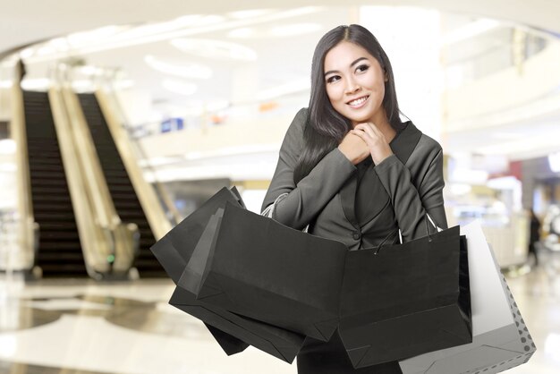 Sacchetti della spesa di trasporto della donna di affari asiatica nel centro commerciale