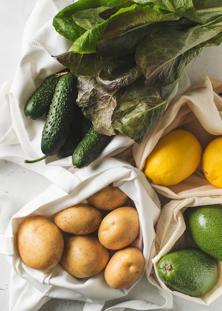 Sacchetti della spesa ecologici del tessuto con le frutta e le verdure su fondo bianco