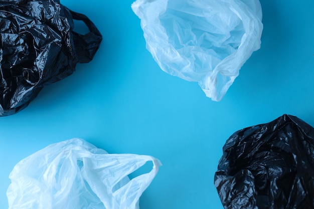 Sacchetti di plastica di diversi colori su sfondo blu. Posto per testo e copia spazio.