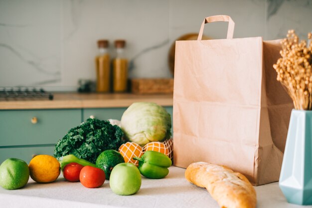 sacchetto di carta della spesa eco con verdure fresche e baguette sul tavolo in cucina moderna.