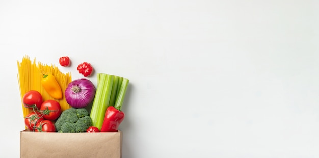 Sacchetto di carta di diversi alimenti sani su un tavolo.