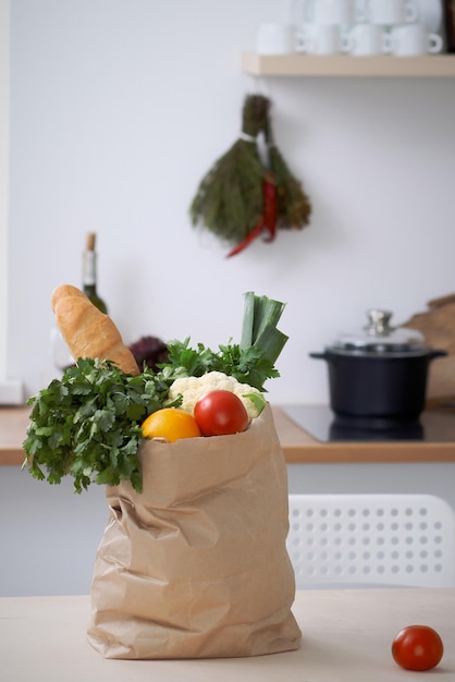 Sacchetto di carta pieno di verdure sul tavolo negli interni della cucina Pasto sano e concetto vegetariano