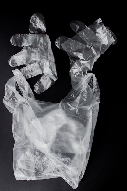 Sacchetto di plastica con manici, guanti, su sfondo nero. Sacchetto di plastica usato per il riciclaggio. Concetto - ecologia, inquinamento del pianeta con polietilene di cellophane di plastica