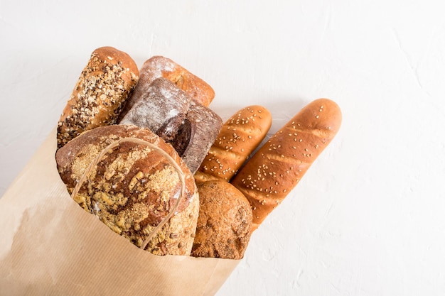 Sacchetto Kraft riempito con vari tipi di pane della panetteria Zero sprechi eco shopping e consegna sfondo bianco