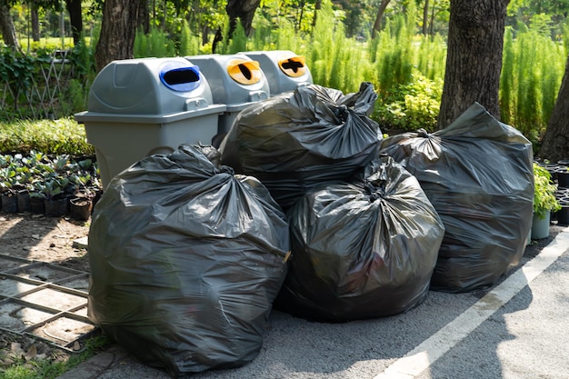 Sacchi della spazzatura di plastica nera di immondizia sul concetto di ambiente pulito della pavimentazione