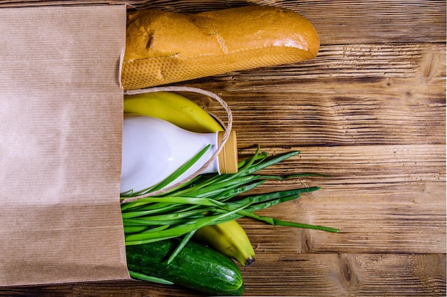 Sacco di carta con cibo diverso dalla drogheria su un tavolo di legno. Concetto di acquisto del supermercato. Vista dall'alto