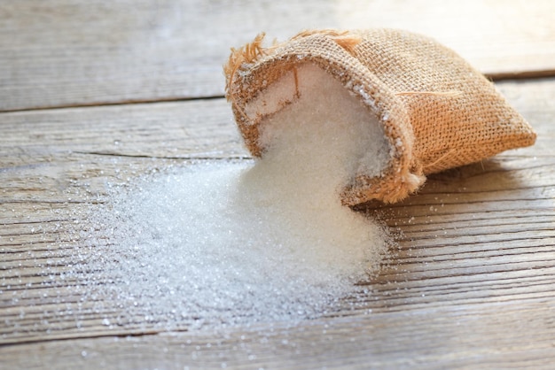 Sacco di zucchero su sfondo di legno zucchero bianco per alimenti e dolci caramella da dessert mucchio di zucchero dolce granulato cristallino