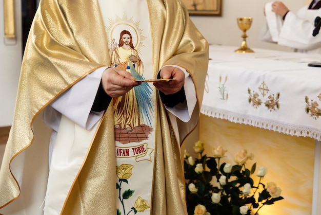 Sacerdote che tiene piatto d'oro per la comunione alla cerimonia di matrimonio in chiesa