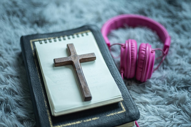 Sacra Bibbia con cuffia e croce di legno leggi e ascolta la voce del concetto cristiano di Dio