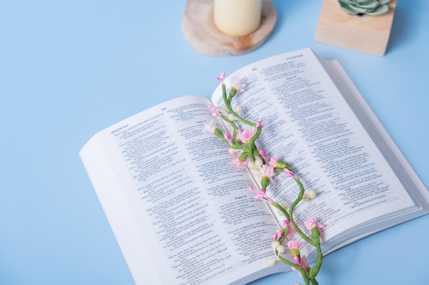 Sacra Bibbia cristiana con fiori decorativi su sfondo blu vista dall'alto piatto