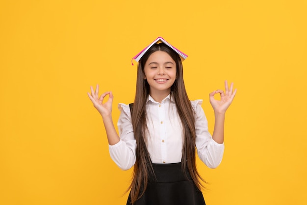 Saggezza ed erudizione. ragazza teenager felice con il libro sulla testa. nerd che medita. di nuovo a scuola. formazione scolastica. stai calmo. lettore bambino intellettuale. letteratura educativa. ragazzo libresco al liceo.