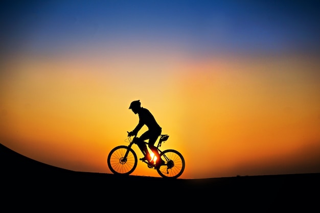 Sagoma del ciclista con la mountain bike sul bel tempo tramonto.