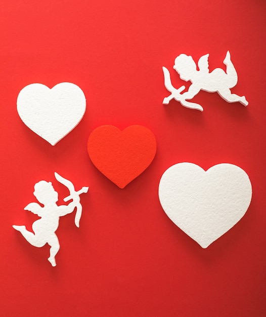 Sagoma di Cupido volante con cuori, regali, striscioni di San Valentino felice, stile di arte della carta. Amour su carta rossa