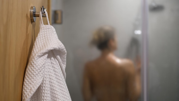 Sagoma di donna snella in doccia e accappatoio bianco
