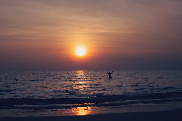 Sagoma di giovane uomo che gioca a paddle board in mare