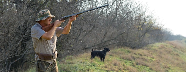 Sagoma di un cacciatore con una pistola tra le canne contro il sole un'imboscata per le anatre con i cani