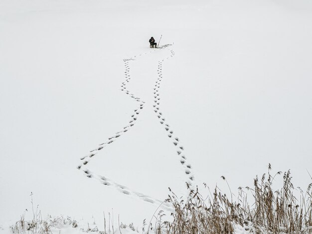 Sagoma di un pescatore su un lago innevato