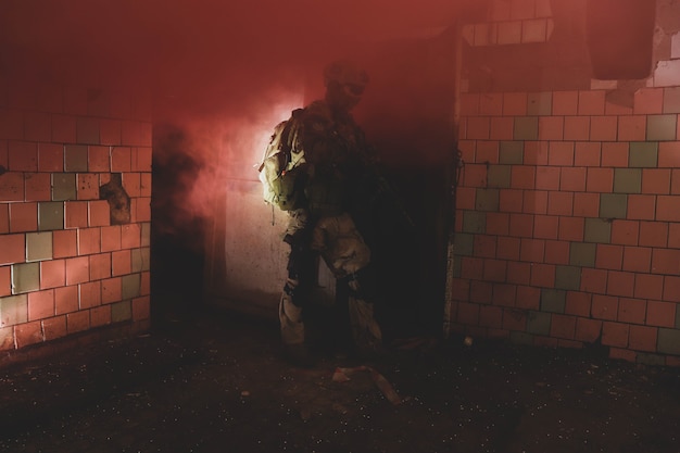sagoma di un uomo in uniforme con un'arma in un vecchio corridoio in fumo rosso