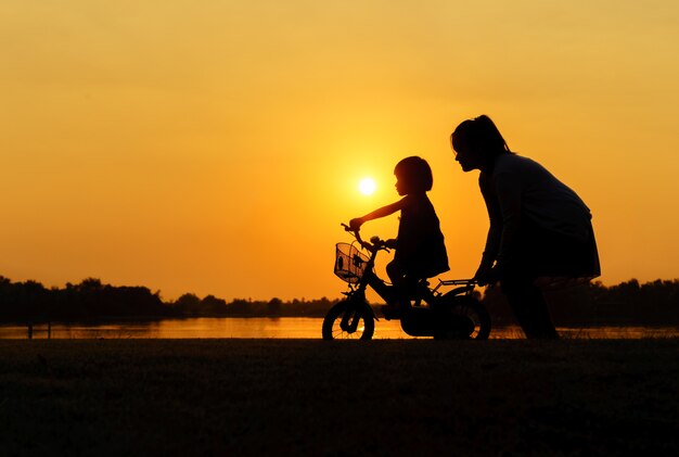 sagoma di una madre che insegna alla figlia ad andare in bicicletta.