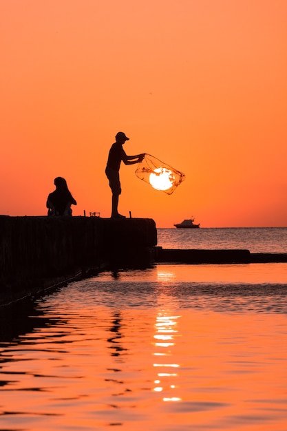 sagoma di una persona che pesca al tramonto