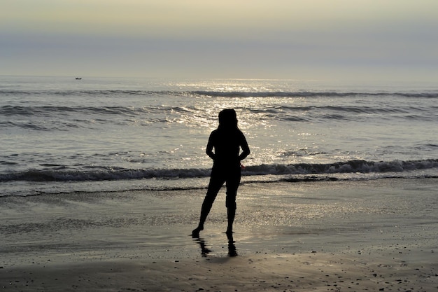 sagoma di una persona in riva al mare al tramonto ora d'oro