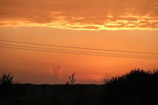 Sagoma scura di torri ad alta tensione con linee elettriche all'alba