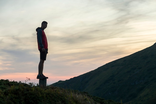 Sagoma scura di un escursionista su una montagna al tramonto in piedi sul vertice come un vincitore.