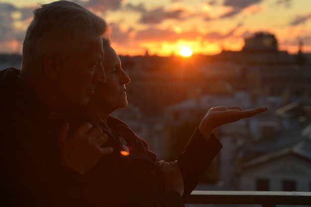 Sagome di coppia di anziani innamorati sopra il cielo al tramonto