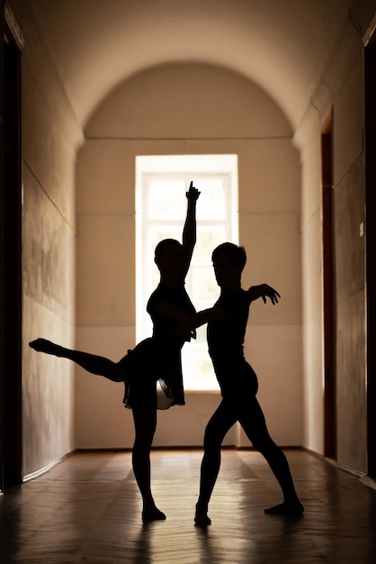 Sagome di due ballerini professionisti che eseguono danza classica nel corridoio di un vecchio teatro. Bellissimo scatto di ballerine eleganti