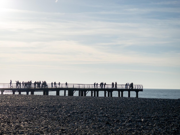 Sagome di persone sul ponte in riva al mare La gente vede il tramonto Costa del mare Molo sul mare