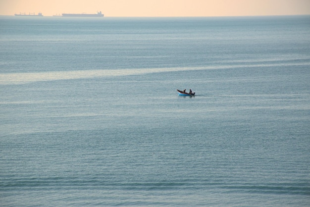 Sagome di pescatori che pescano nel mare infinito navigando su una barcaMar NeroRussia