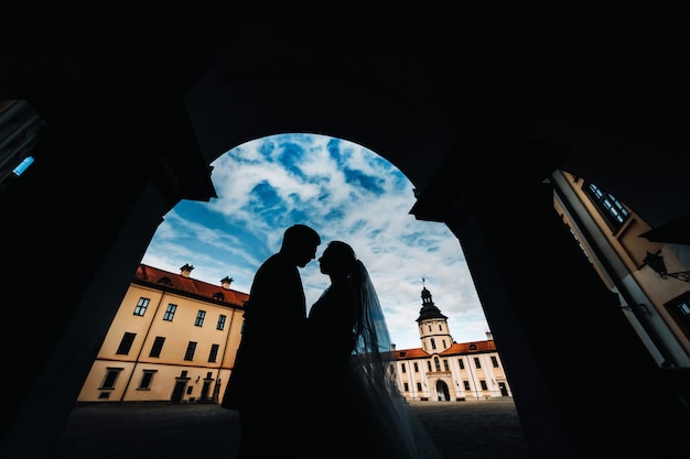 Sagome di una coppia innamorata al tramonto sullo sfondo del castello di Nesvizh