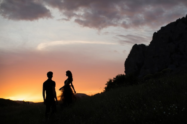 Sagome di una giovane coppia di amanti al tramonto nei raggi del sole al tramonto