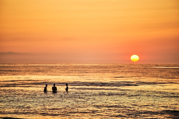 Sagome di unione giovanile in Ocean's Embrace Sagome di un giovane gruppo di persone che nuotano nell'oceano al tramonto