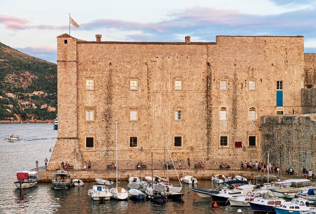 Saint John Fort e barche a vela nel porto vecchio con persone nel mare Adriatico a Dubrovnik, Croazia