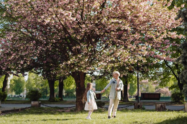 Sakura sbocciata La giovane madre con il suo bambino si diverte nel parco vicino al fiore di ciliegio di sakura