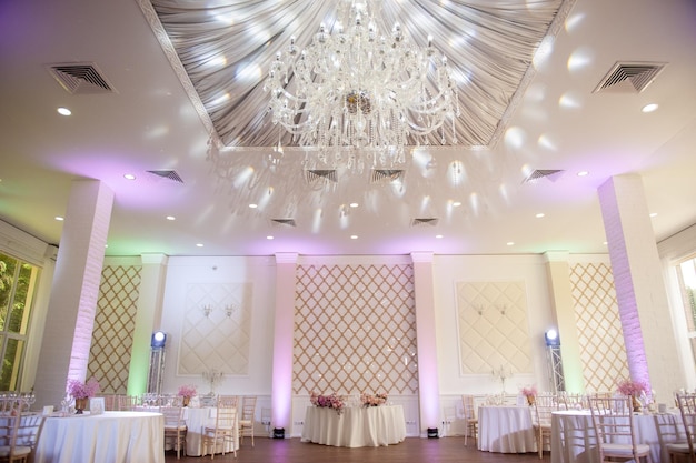 Sala banchetti bianca per matrimoni con tavoli rotondi decorati con fiori freschi