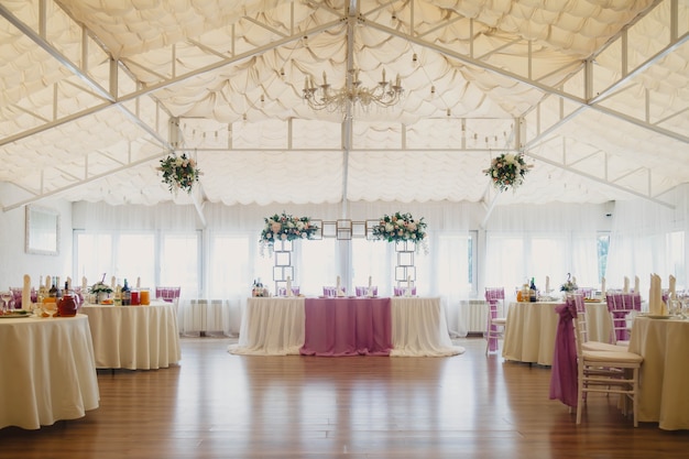 Sala coperta per ricevimenti di nozze con tavoli e addobbi floreali